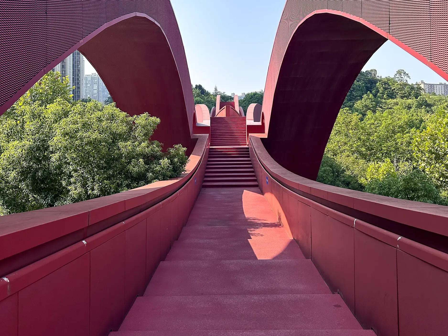 Die leuchtend rote Glücksknotenbrücke in Changsha mit ihrer wellenförmigen Konstruktion und den Treppenaufgängen.