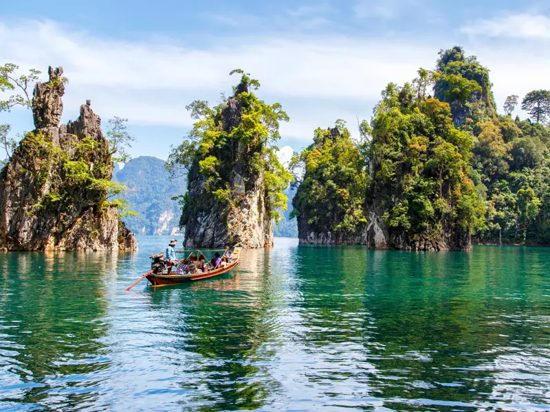 Eine Reisegruppe auf einer Singlereise erkundet mit dem Longtailboot die Karstfelsen auf dem Chiao-Lan-See im Khao Sok-Nationalpark.