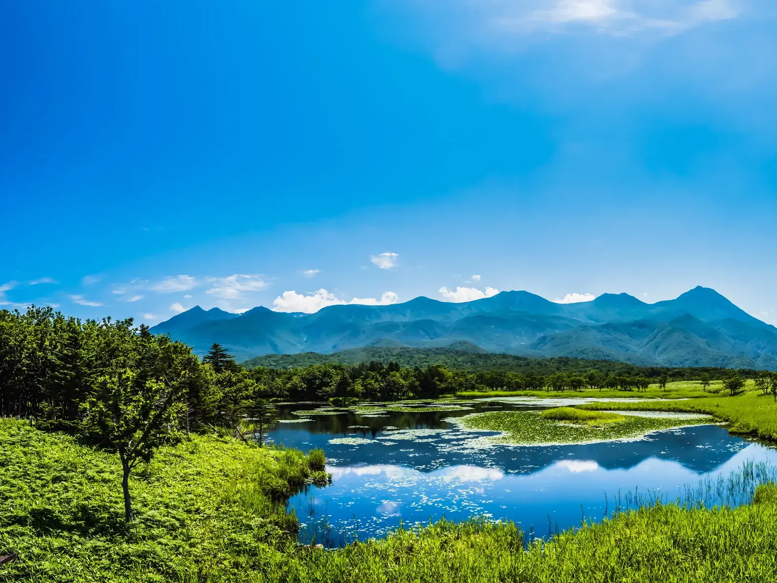 Idyllischer Blick auf einen der Shiretoko Fünf Seen in Hokkaido, in dem sich die umliegende Bergkette Japans spiegelt.