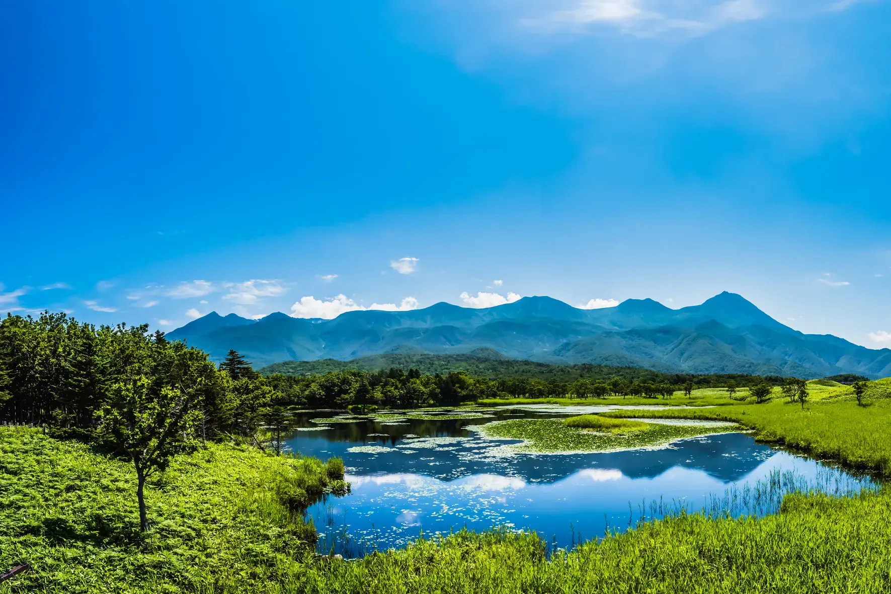 Idyllischer Blick auf einen der Shiretoko Fünf Seen in Hokkaido, in dem sich die umliegende Bergkette Japans spiegelt.