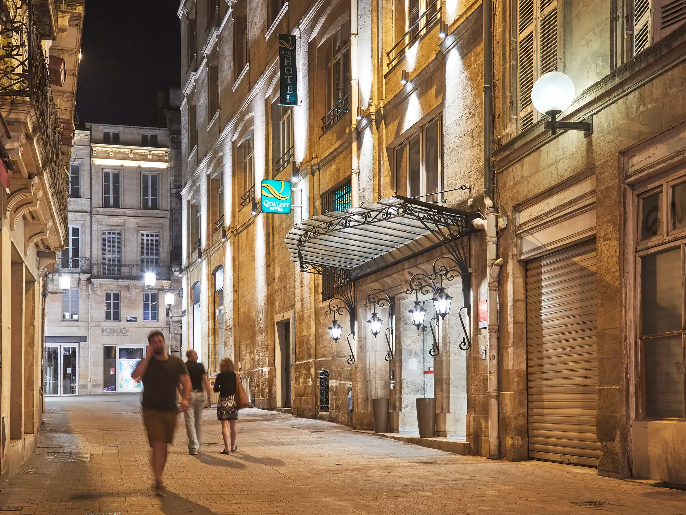 Stimmungsvoll beleuchteter Eingang des Quality Hotel Bordeaux Centre in einer historischen Gasse in der Innenstadt von Bordeaux.