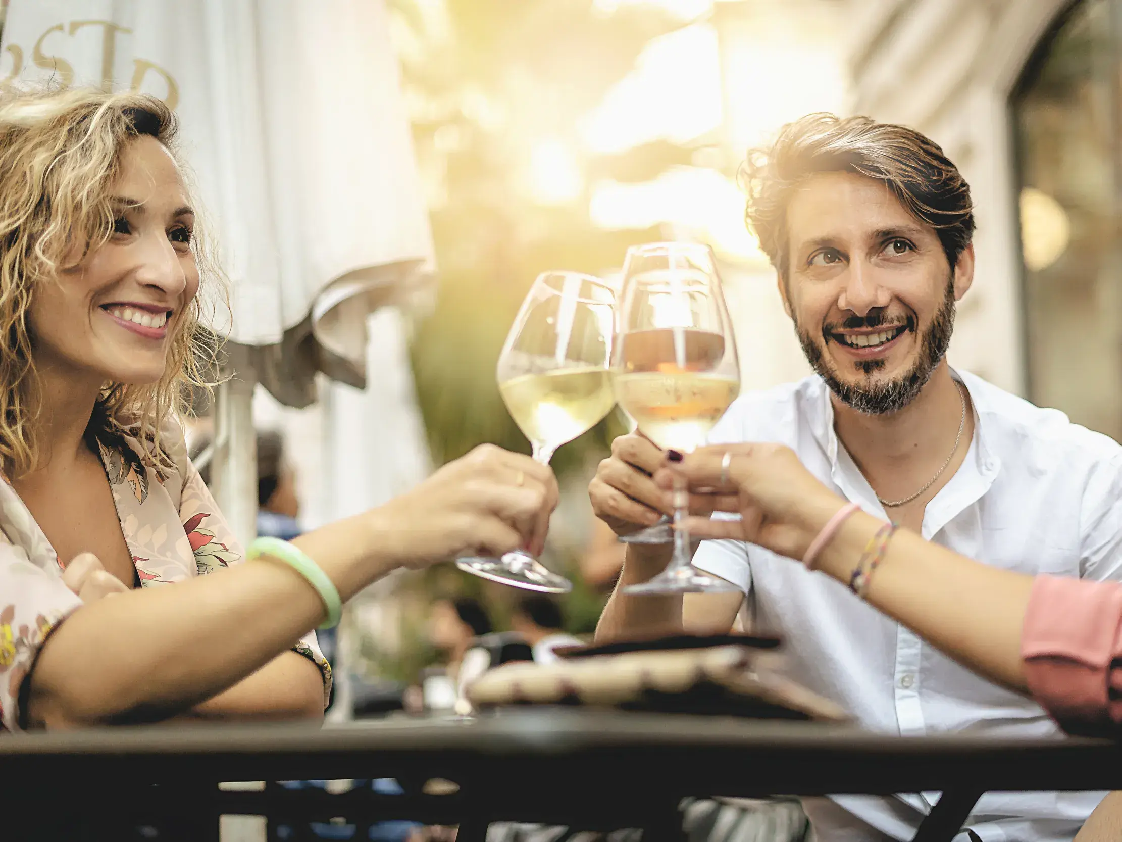 Eine kleine Reisegruppe genießt das Savoir-vivre in der Provence und stößt in einem Straßencafé mit Weißwein an.