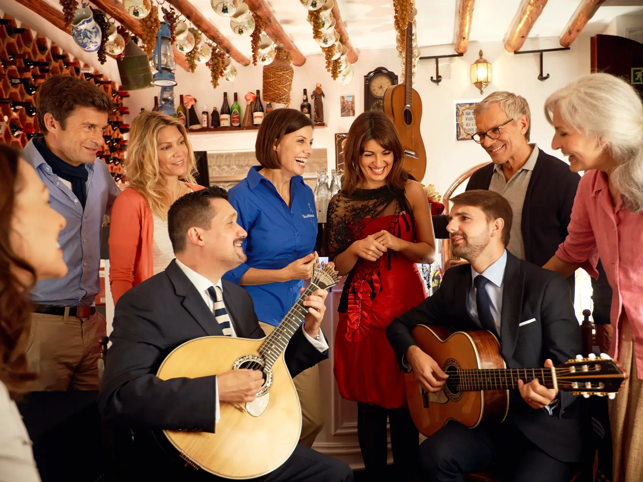 Eine Studiosus Reisegruppe lauscht mit ihrer Reiseleiterin einem Konzert mit portugiesischer Gitarre in einer rustikalen Tasca.