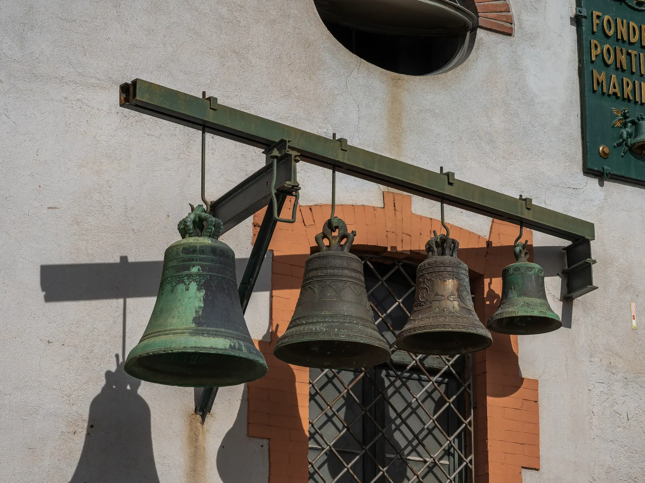 Vier unterschiedlich große Glocken mit Patina hängen an der Fassade der historischen Glockengießerei Marinelli in Agnone.