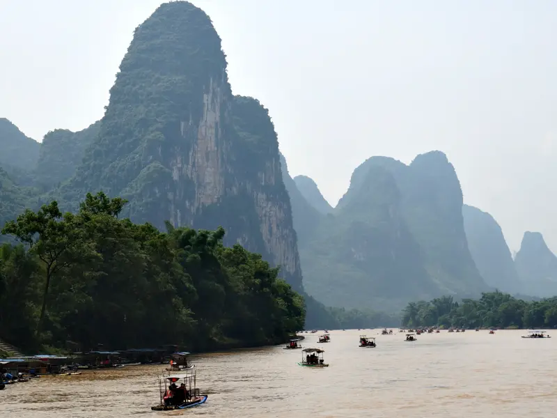 Zahlreiche Bambusflöße mit Reisenden auf dem Li-Fluss vor der spektakulären Karstlandschaft bei Yangshuo in China.