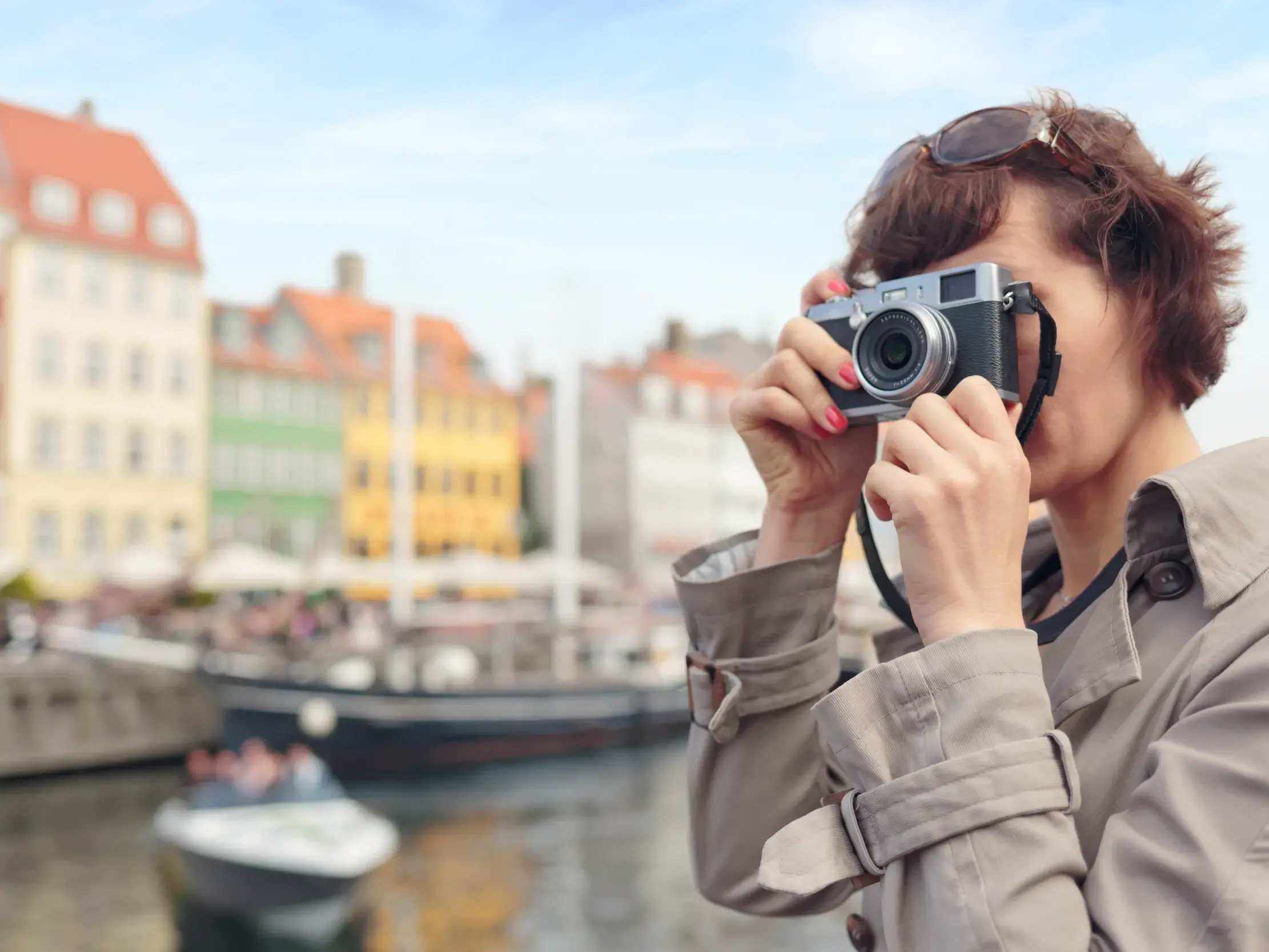 Eine Reisende fotografiert auf ihrer Studienreise die bunten Giebelhäuser entlang des Kanals von Nyhavn in Kopenhagen.