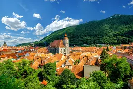Panoramablick auf die Altstadt von Kronstadt mit der gotischen Schwarzen Kirche in Siebenbürgen vor einem bewaldeten Berg.