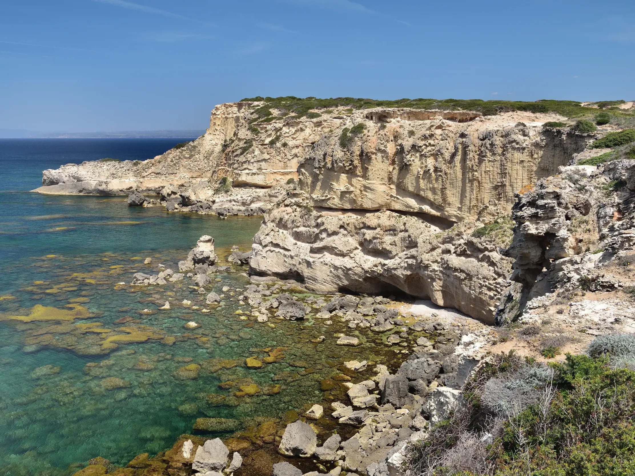 Helle Felsklippen an der Küste der Sinis-Halbinsel auf Sardinien, das klare, türkisfarbene Meer umspült die Felsen.
