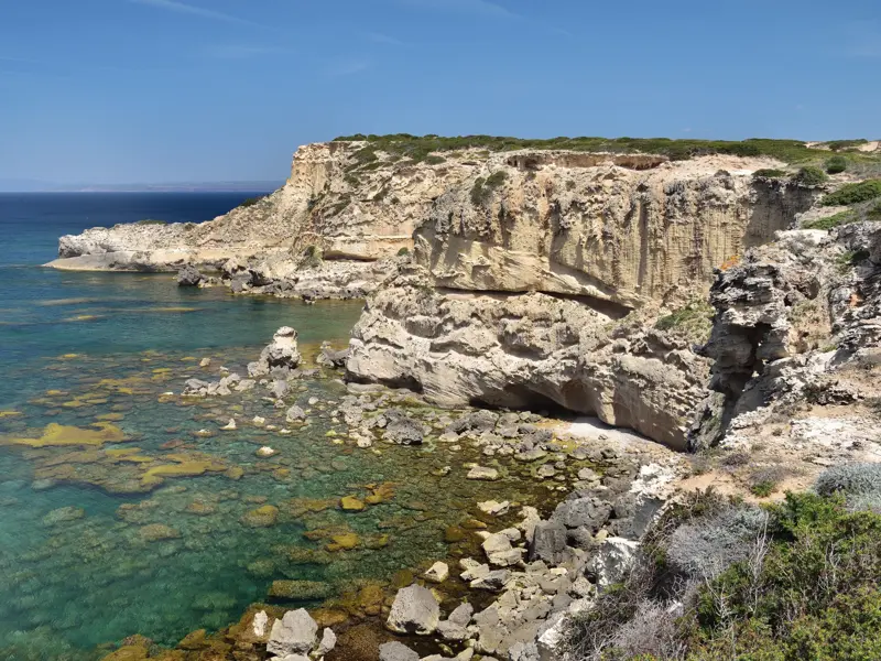 Helle Felsklippen an der Küste der Sinis-Halbinsel auf Sardinien, das klare, türkisfarbene Meer umspült die Felsen.