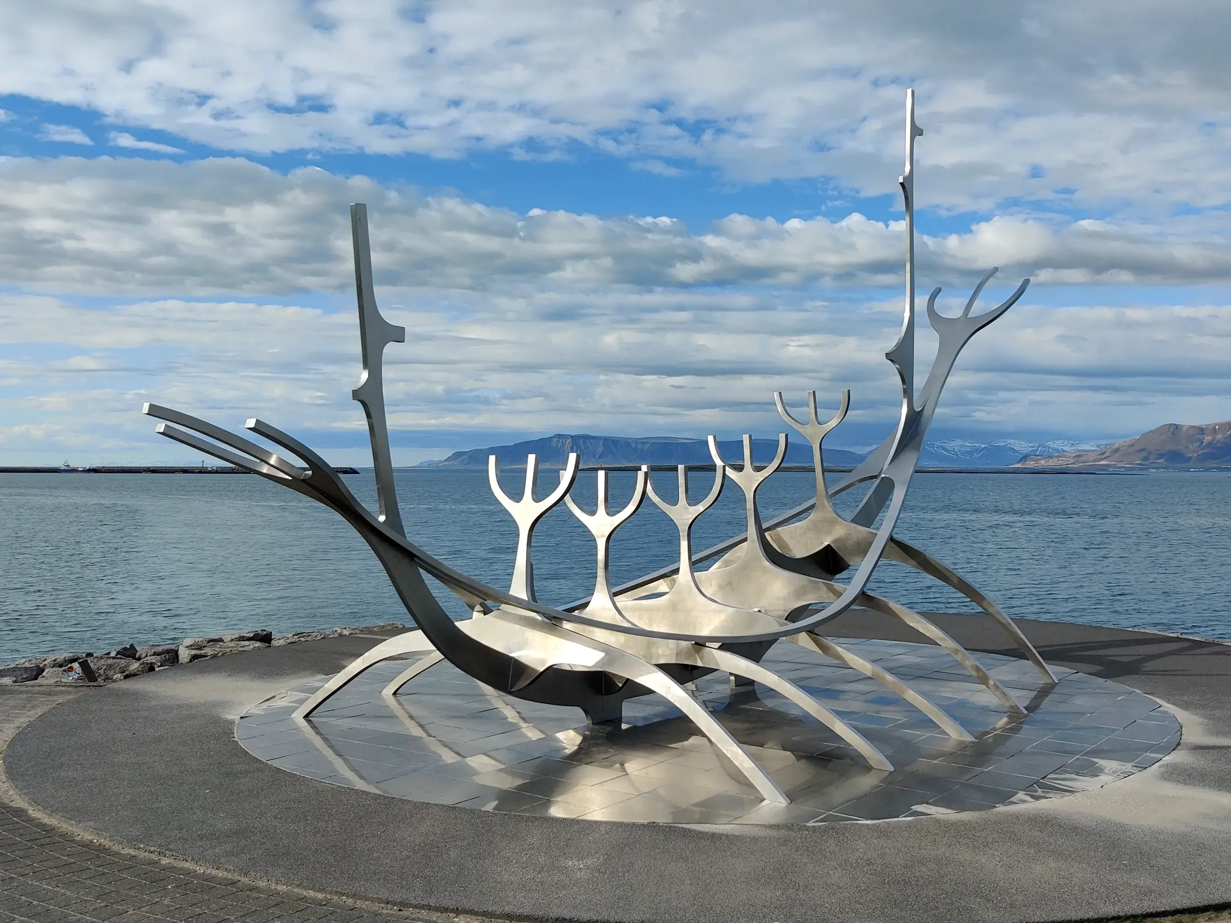 Die stählerne Sonnenschiff-Skulptur Solfar an der Küste von Reykjavik mit Blick auf die Bucht und Berge Islands.