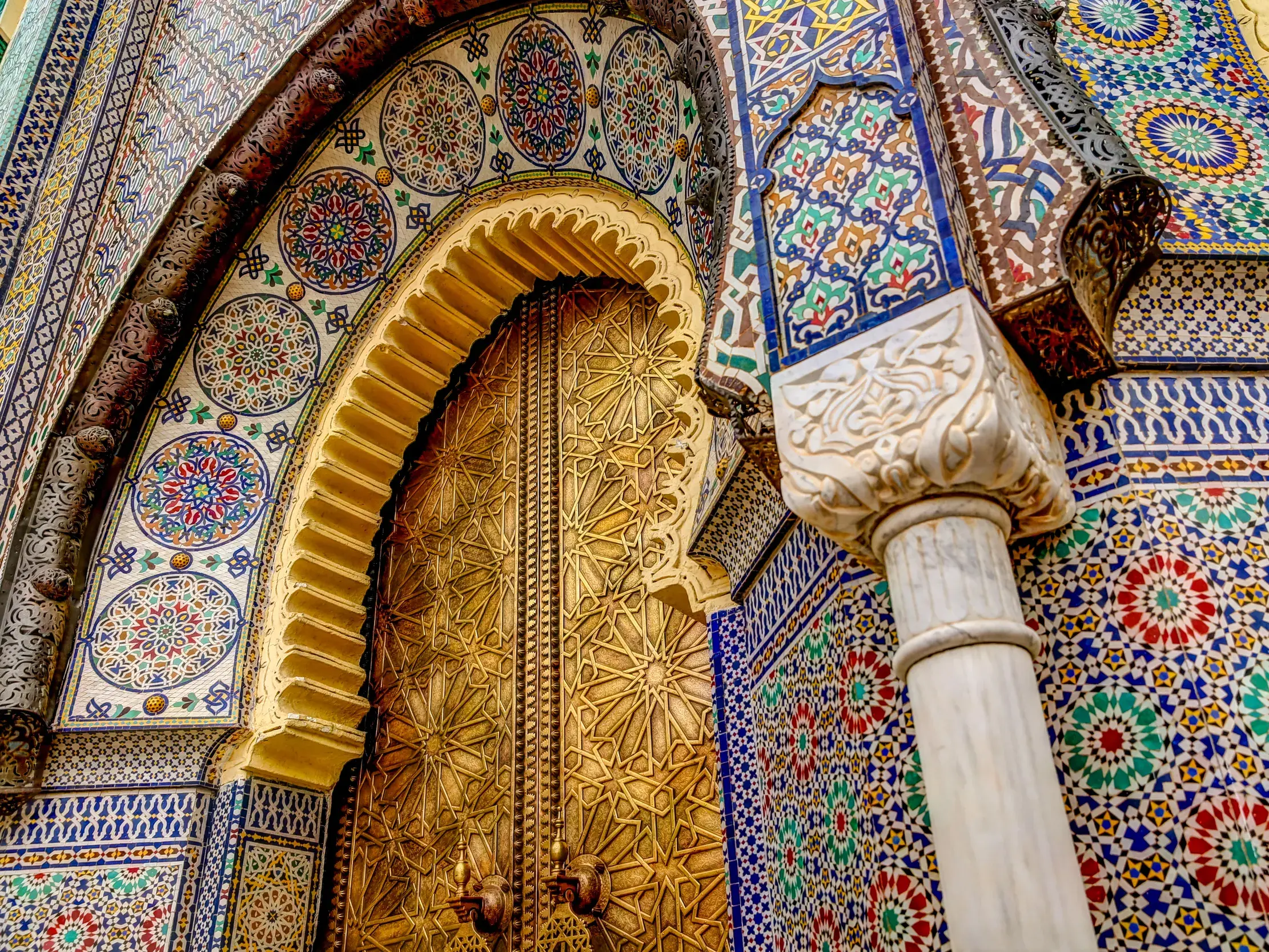 Detailaufnahme der prächtigen marokkanischen Architektur mit goldenem Tor und bunten Zellij-Mosaiken in der Königsstadt Fès.