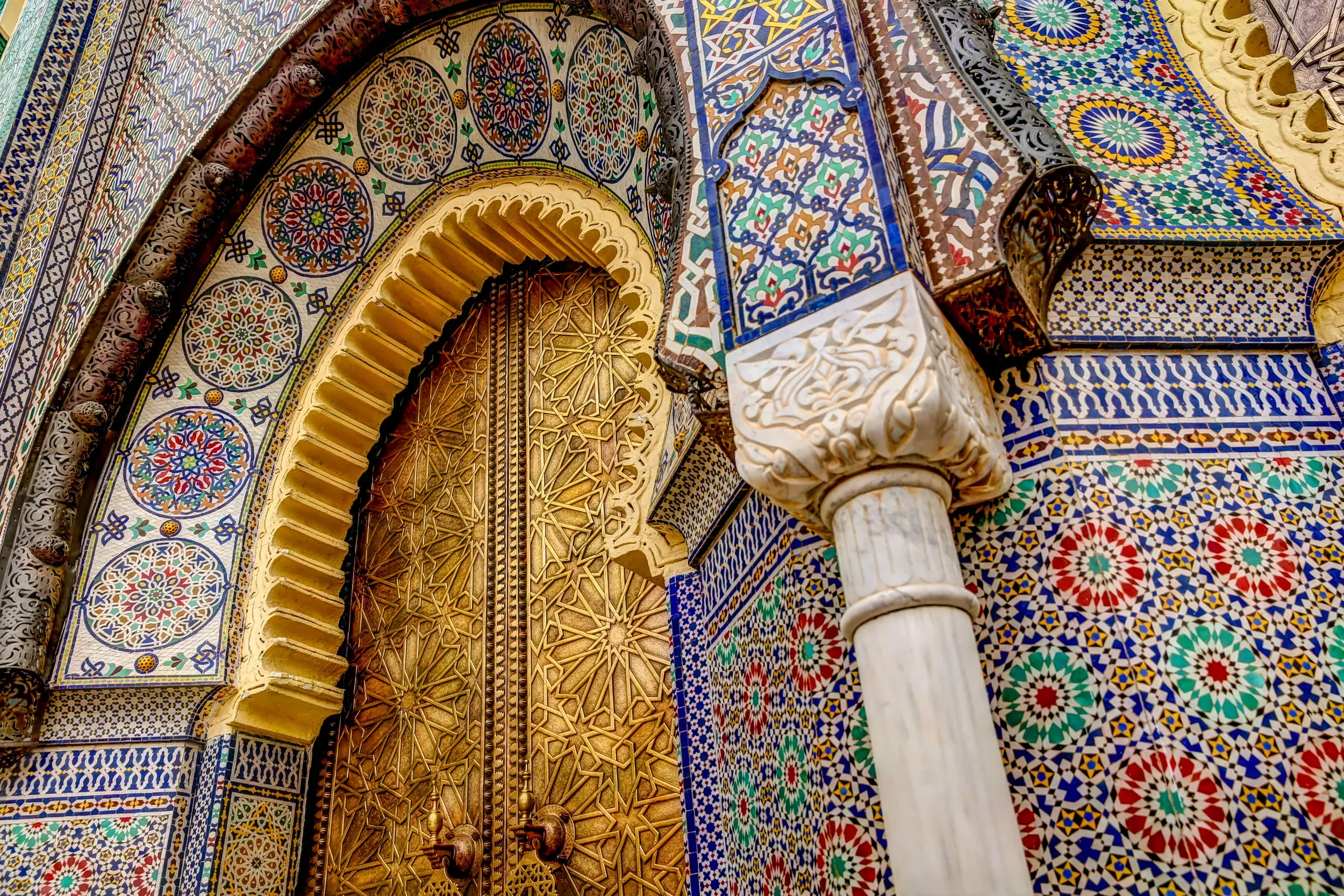 Detailaufnahme der prächtigen marokkanischen Architektur mit goldenem Tor und bunten Zellij-Mosaiken in der Königsstadt Fès.