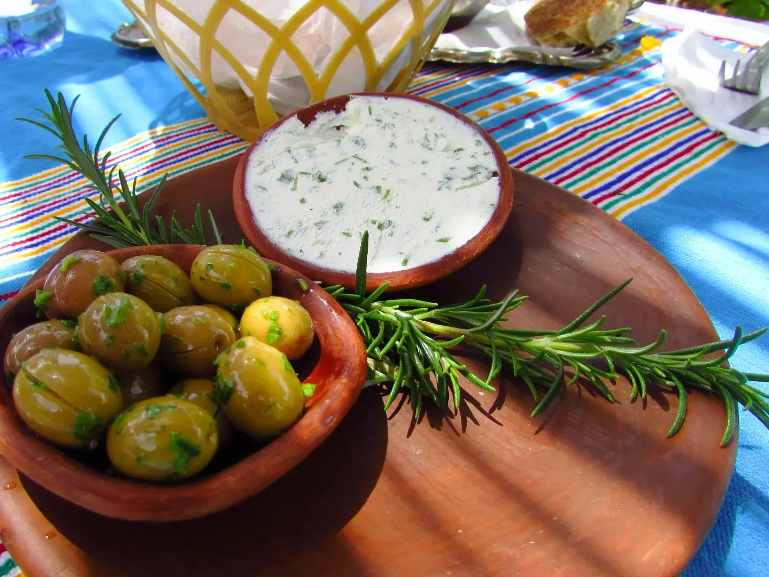 Traditionelle marokkanische Vorspeise mit Kräuteroliven und Joghurtdip in Tonschalen, garniert mit frischem Rosmarin.