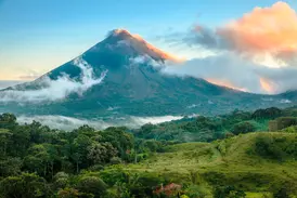 Der majestätische Vulkan Arenal in Costa Rica, dessen Gipfel von Wolken im Morgenlicht umspielt wird, über grünen Regenwäldern.