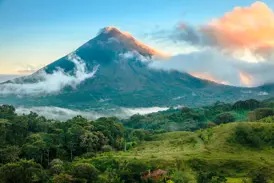 Der majestätische Vulkan Arenal in Costa Rica, dessen Gipfel von Wolken im Morgenlicht umspielt wird, über grünen Regenwäldern.