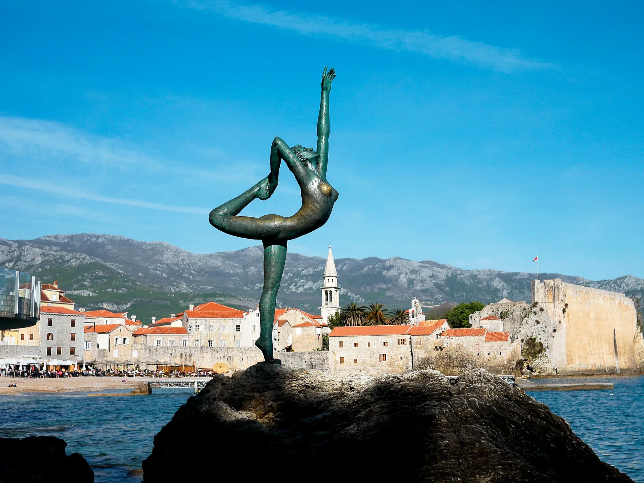 Die bronzene Ballerina-Statue auf einem Felsen vor der historischen Altstadt von Budva an der Adriaküste Montenegros.