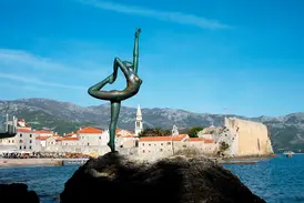 Die bronzene Ballerina-Statue auf einem Felsen vor der historischen Altstadt von Budva an der Adriaküste Montenegros.