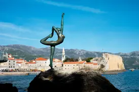 Die bronzene Ballerina-Statue auf einem Felsen vor der historischen Altstadt von Budva an der Adriaküste Montenegros.