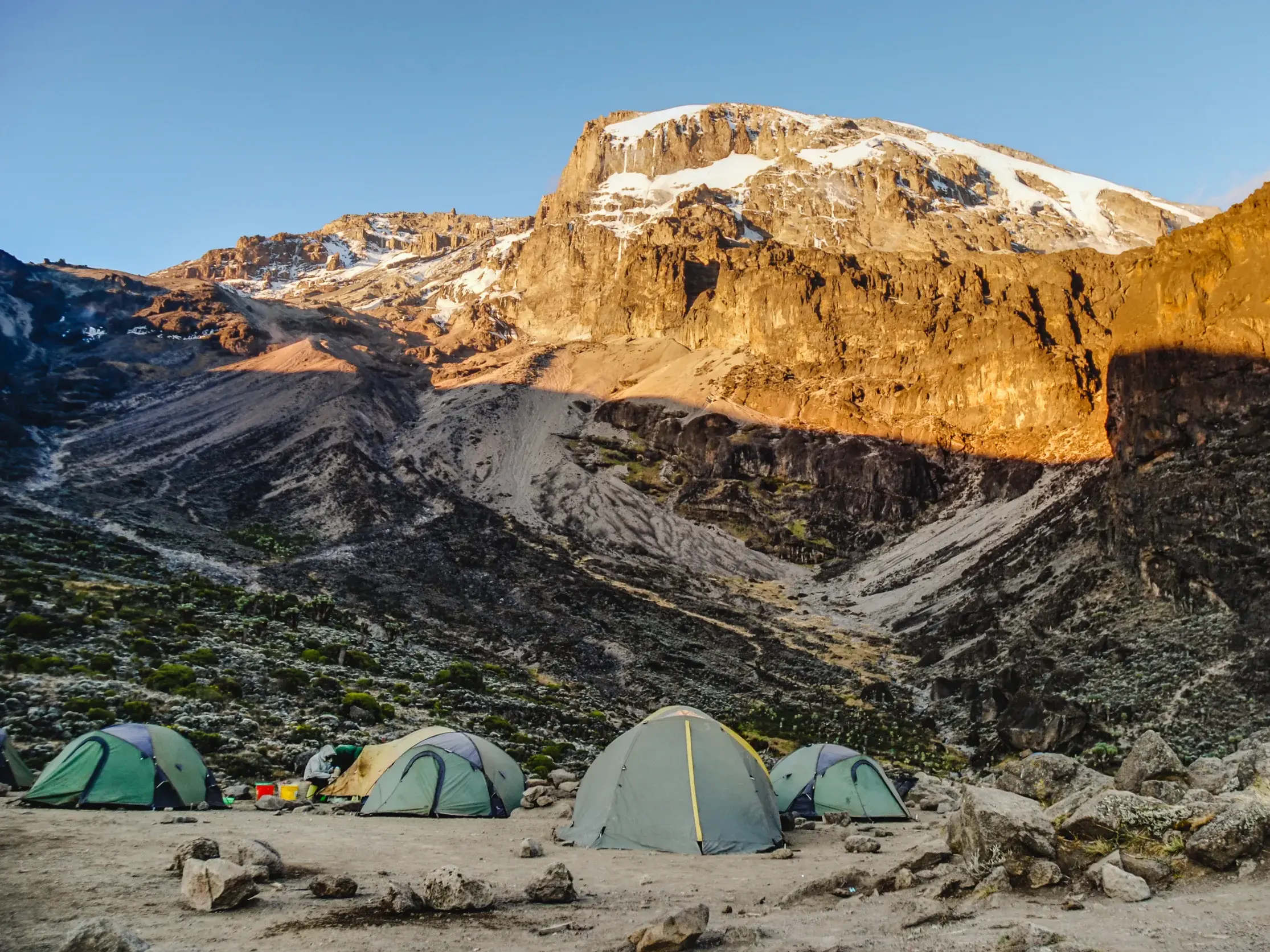 Trekking-Zelte im Barafu Camp, während die Morgensonne den schneebedeckten Gipfel des Kilimanjaro beleuchtet.