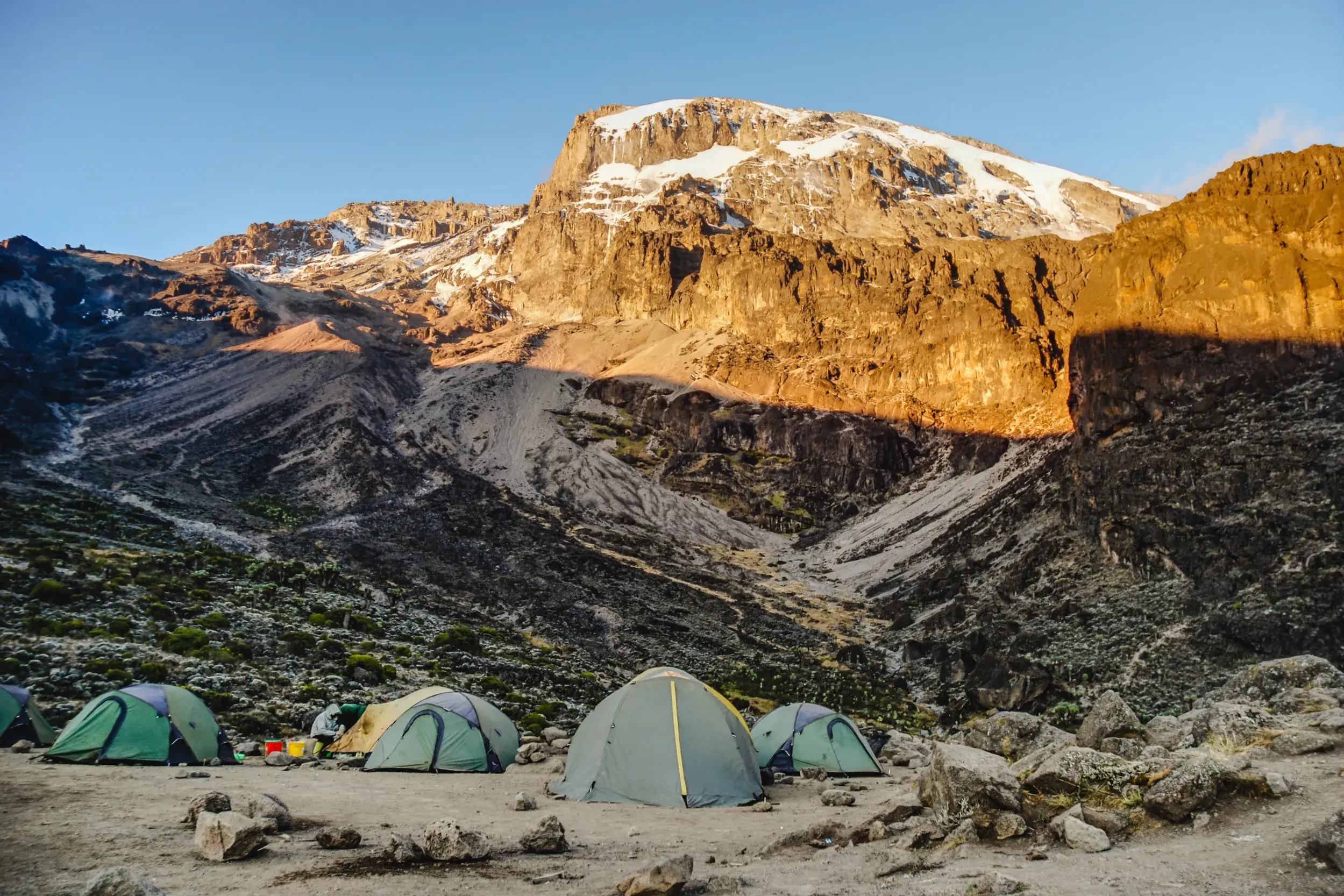 Trekking-Zelte im Barafu Camp, während die Morgensonne den schneebedeckten Gipfel des Kilimanjaro beleuchtet.