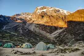Trekking-Zelte im Barafu Camp, während die Morgensonne den schneebedeckten Gipfel des Kilimanjaro beleuchtet.