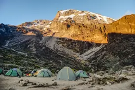 Trekking-Zelte im Barafu Camp, während die Morgensonne den schneebedeckten Gipfel des Kilimanjaro beleuchtet.