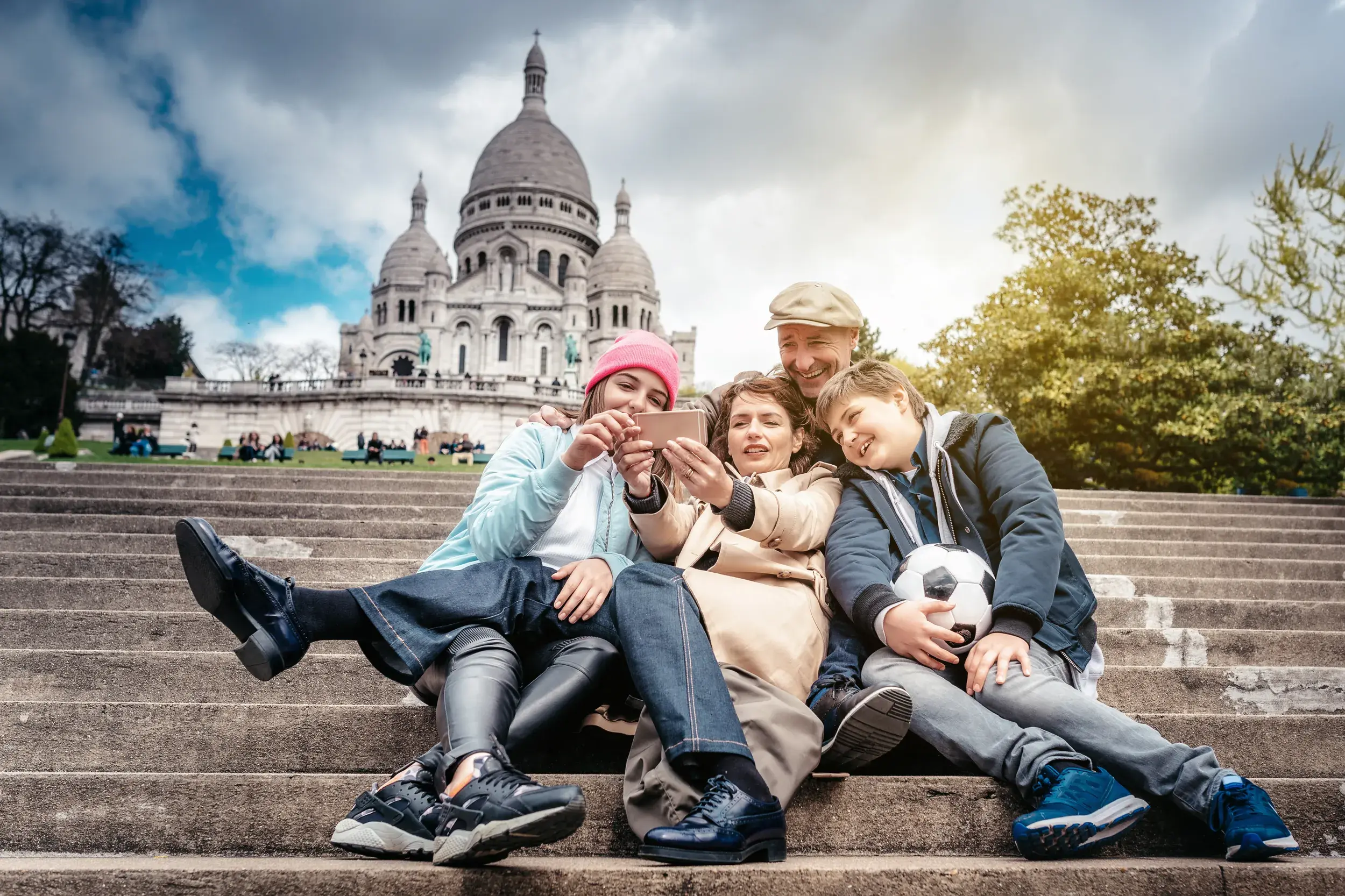 Eine fröhliche Familie sitzt während der Studiosus family Reise auf den Stufen vor Sacré Coeur auf dem Montmartre.