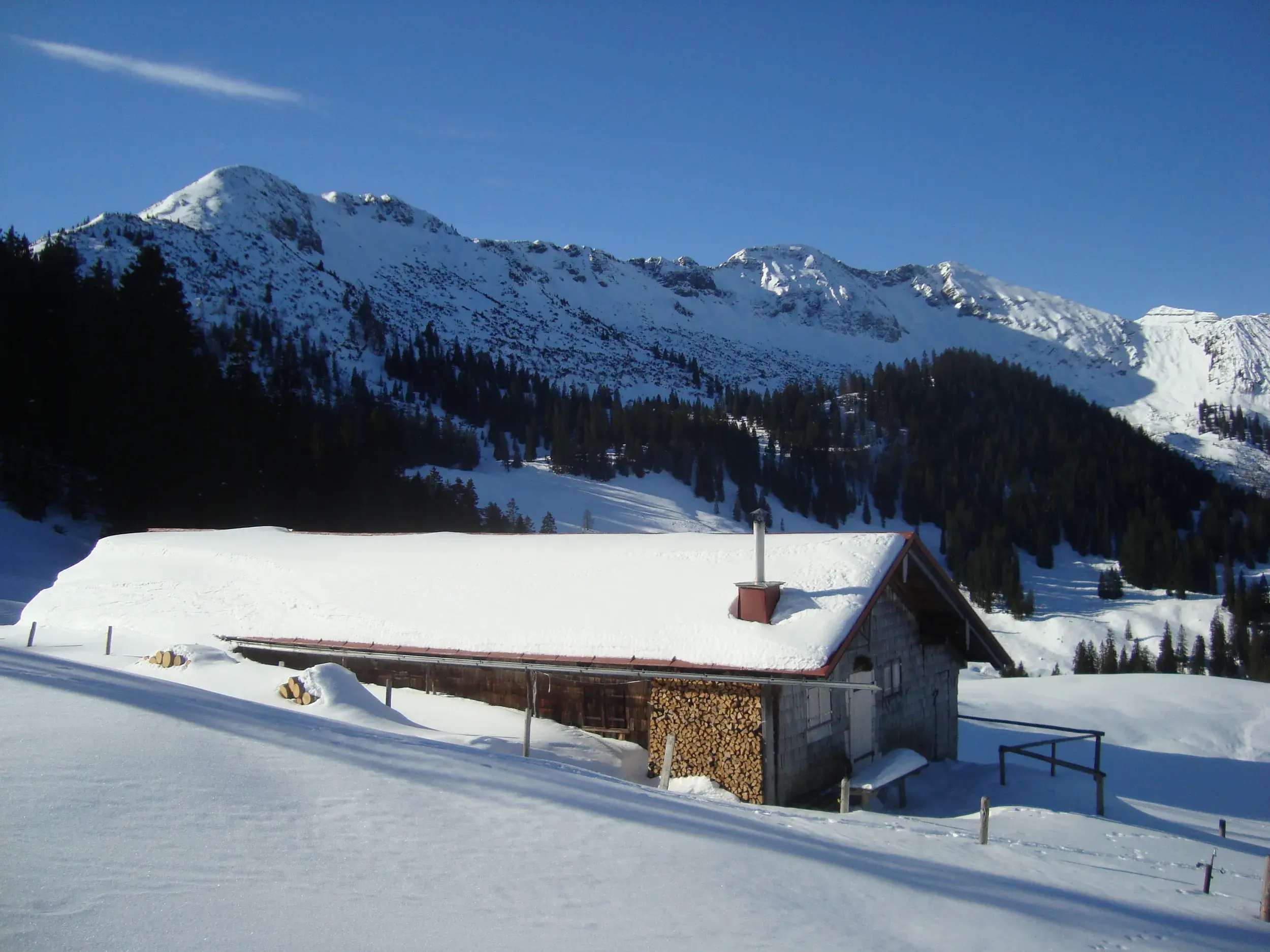 Tief verschneite Rontalalm vor der Nördlichen Karwendelkette im Karwendel an einem sonnigen Wintertag bei einer Wanderung.
