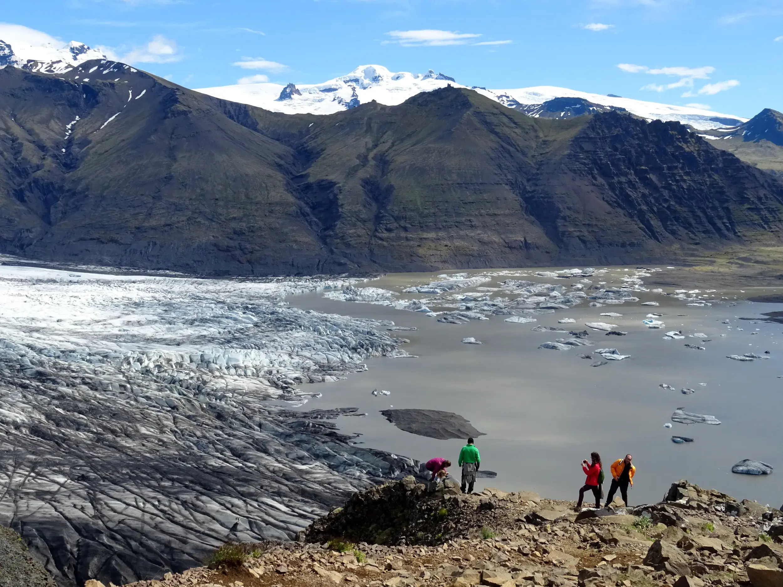 Wanderer einer Hauser Gruppenreise genießen den Ausblick auf eine Gletscherlagune mit Eisbergen im Vatnajökull Nationalpark.