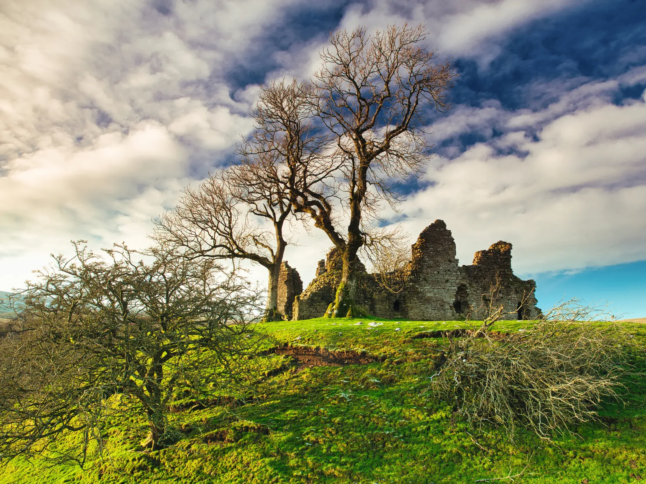 Die historische Ruine der Shap Abbey auf einem grünen Hügel unter dramatischem Himmel auf dem Coast to Coast Walk in England.
