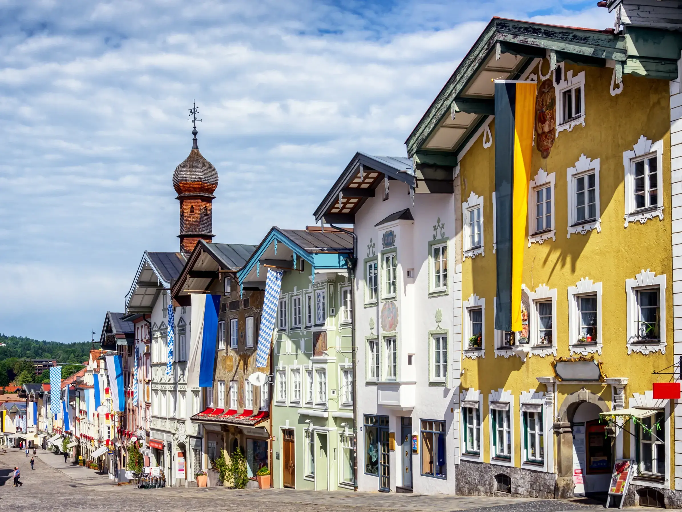 Historische Marktstraße in Bad Tölz mit ihren farbenfrohen, verzierten Bürgerhäusern und wehenden bayerischen Fahnen.