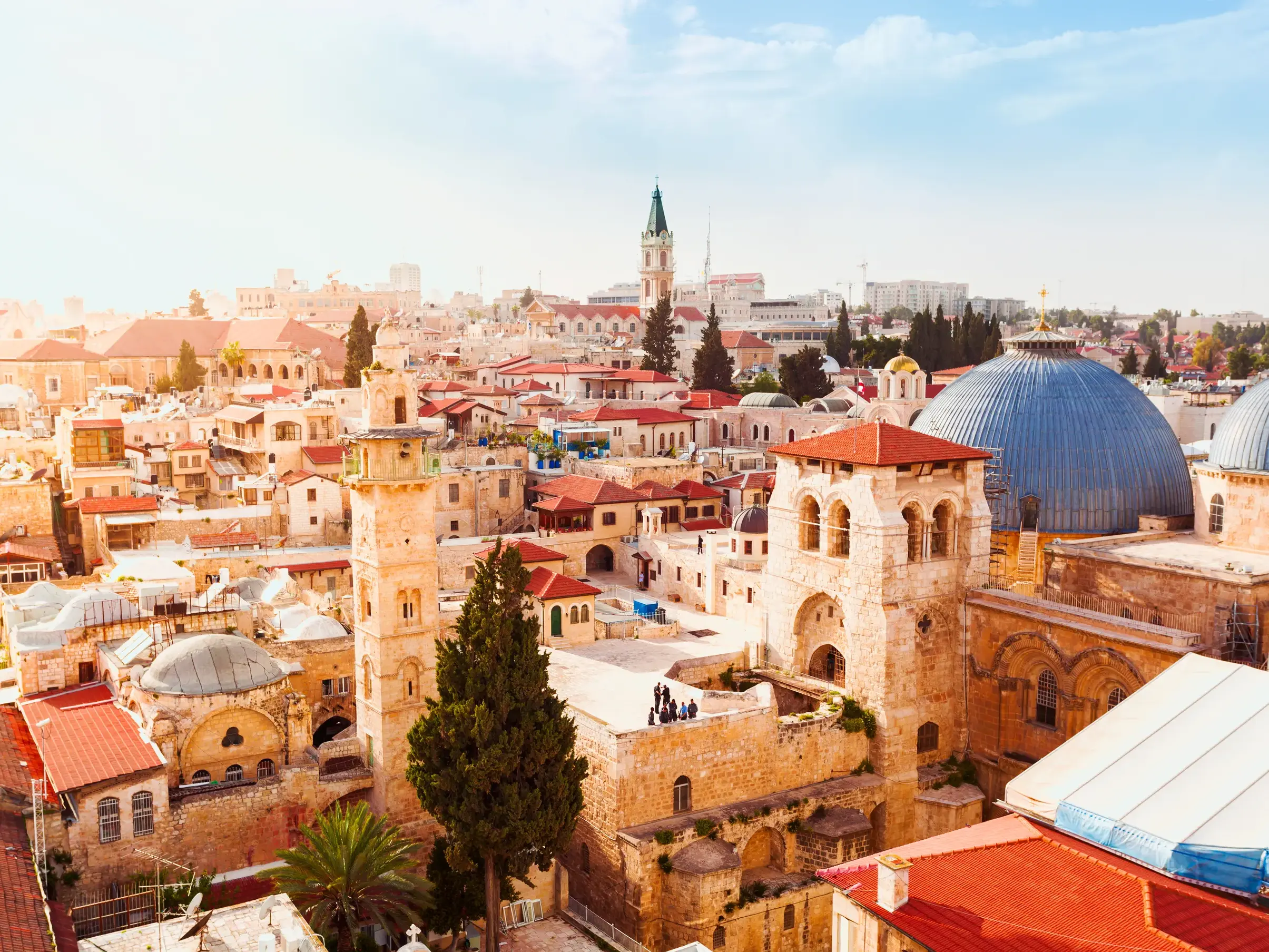 Weitblick über die historische Altstadt von Jerusalem mit der blauen Kuppel der Grabeskirche und Steintürmen bei Sonnenschein.