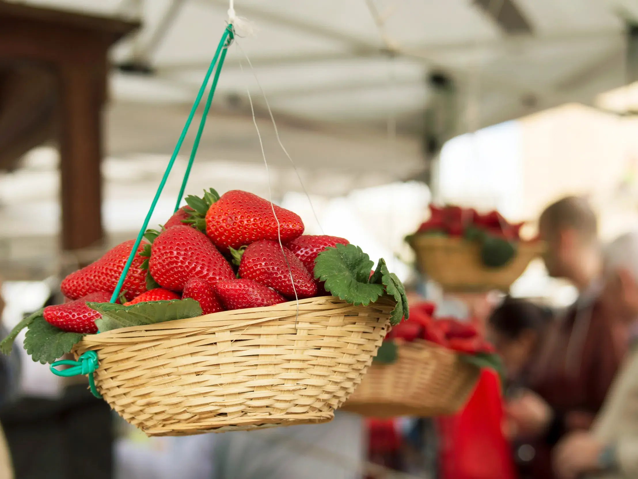 Hängender Korb voller frischer, roter Erdbeeren auf dem lebhaften Markt im Fischerdorf Marsaxlokk auf Malta.