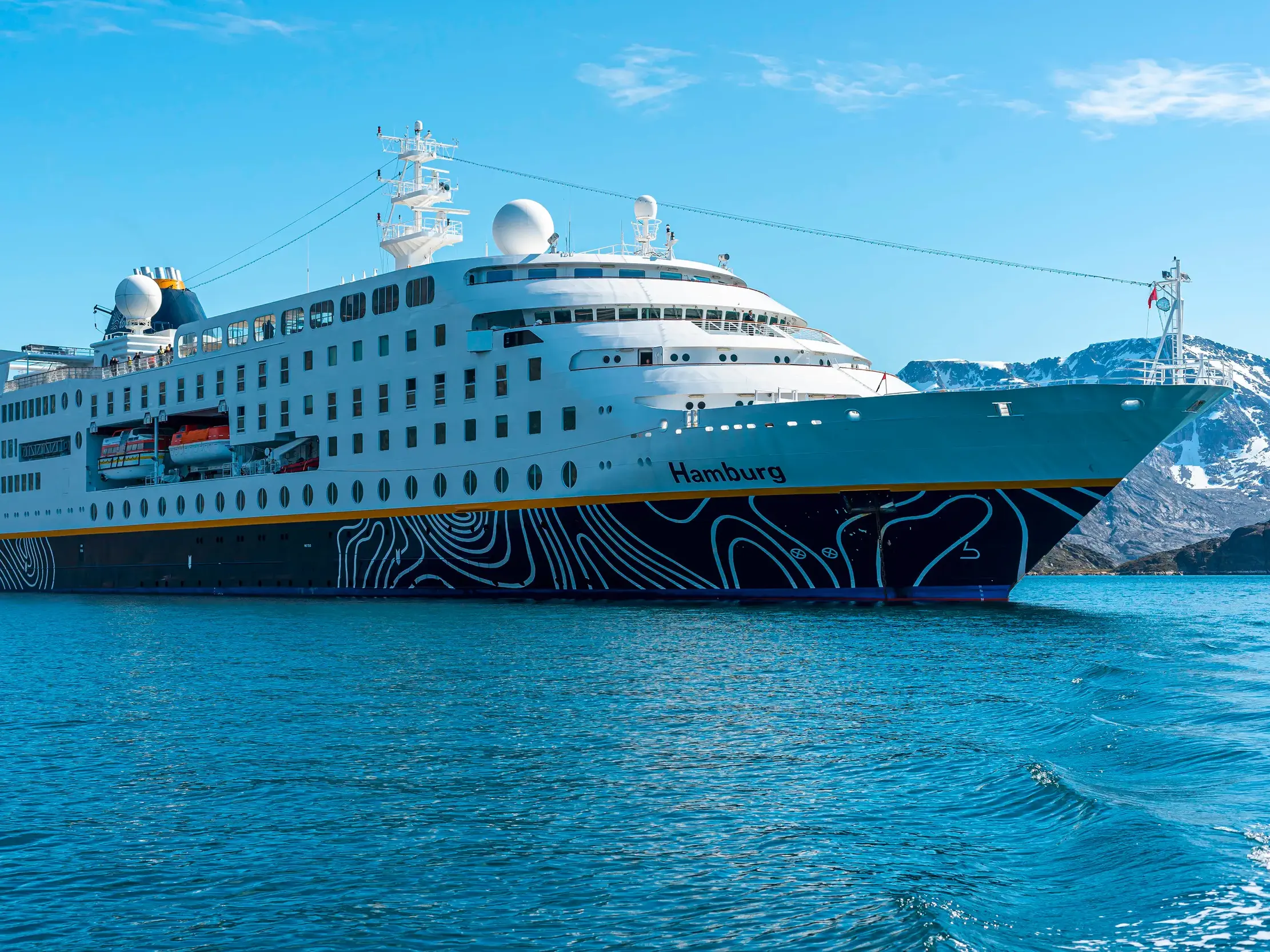 Das Kreuzfahrtschiff MS Hamburg fährt bei Sonnenschein auf ruhiger See vor der Küste
