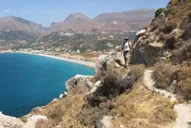Wanderer auf einem Küstenpfad des Fernwanderwegs E4 mit Panoramablick auf eine Bucht an Kretas Südküste.