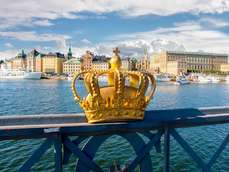 Eine goldene Krone ziert die Skeppsholmsbron vor der Kulisse der Altstadt Gamla Stan und des Königlichen Schlosses Stockholm.