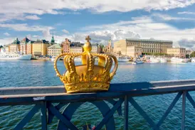 Eine goldene Krone ziert die Skeppsholmsbron vor der Kulisse der Altstadt Gamla Stan und des Königlichen Schlosses Stockholm.