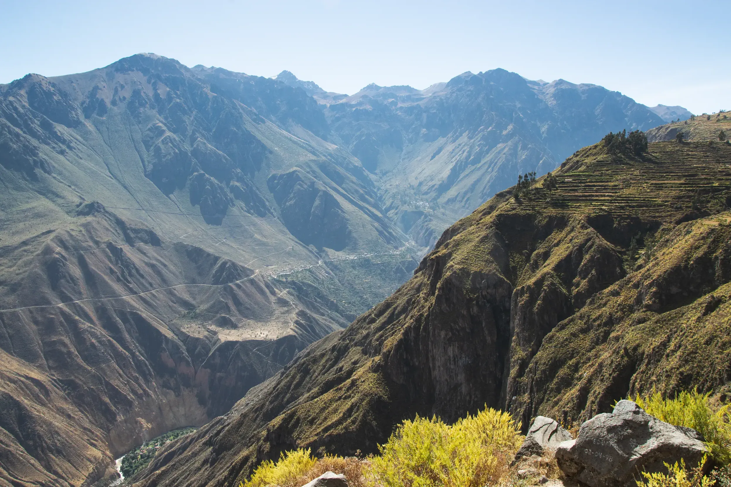 Weite Aussicht beim Wandern in den peruanischen Anden über die tiefen Schluchten und grünen Terrassen des Colca Canyon.