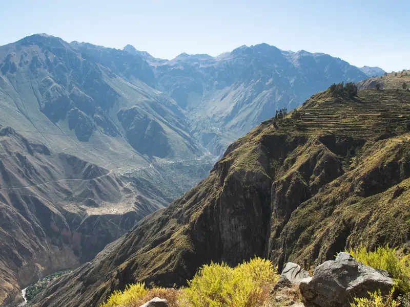 Weite Aussicht beim Wandern in den peruanischen Anden über die tiefen Schluchten und grünen Terrassen des Colca Canyon.